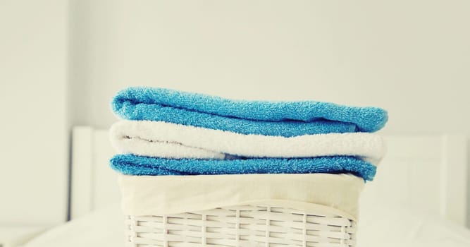 Wicker laundry basket with clean folded towels on the bed