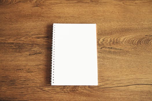 Top view of white blank notebook on wooden table