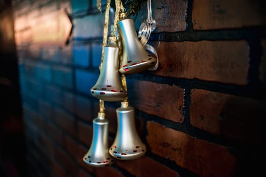 Christmas bells hang as a decor on the Christmas ribbon on the brick wall