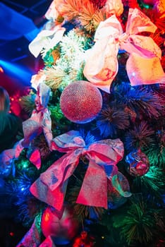 artificial Christmas tree the club decorated with baubles and bows with colorful lighting