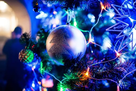 Christmas toy ball on Christmas branches artificial Christmas tree with blurred background of lights garland closeup