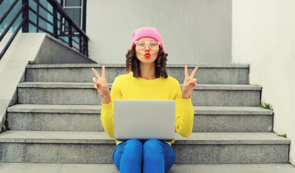 Portrait of modern cool young woman with laptop in the city