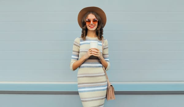 Stylish young woman posing in round hat, knitted dress, sunglasses in the city