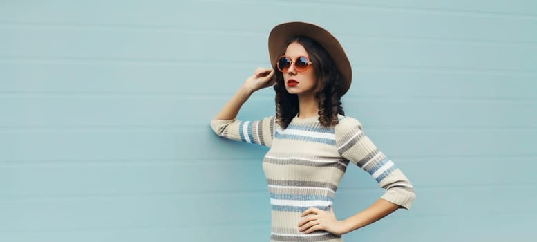 Stylish young woman posing in round hat, knitted dress, sunglasses in the city