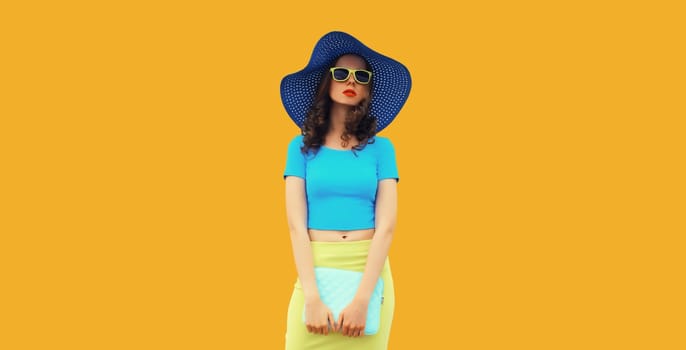 Beautiful caucasian young woman model posing with handbag clutch in summer straw hat on yellow studio background