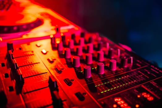 mixer for music in the night club DJ closeup with red backlight