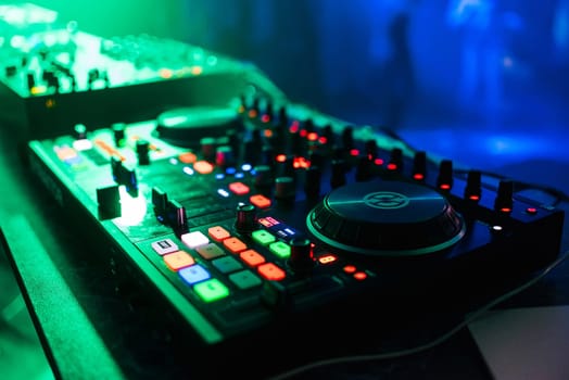professional control panel and mixing music under the green lights in the nightclub at a party
