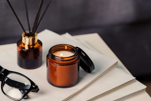 Aromatic reed freshener and candle on table in room close up