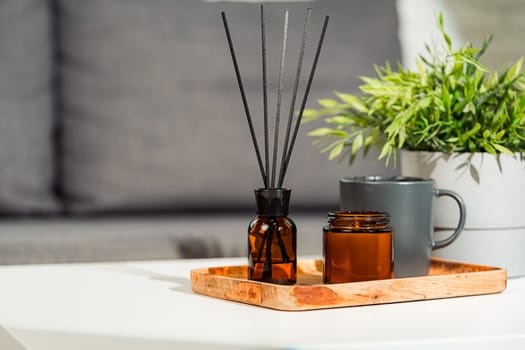 Aromatic reed freshener and candle on table in room close up