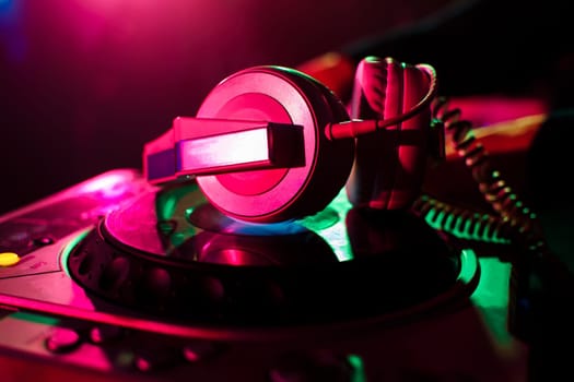 professional headphones and mixer DJ for music in a nightclub on the background color lasers