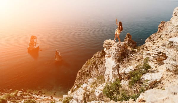 Woman travel sea. Happy tourist taking picture outdoors for memories. Woman traveler looks at the edge of the cliff on the sea bay of mountains, sharing travel adventure journey.