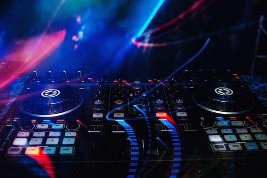 mixer and DJ booth in the nightclub at party c of bright multicolored effects with a dark background