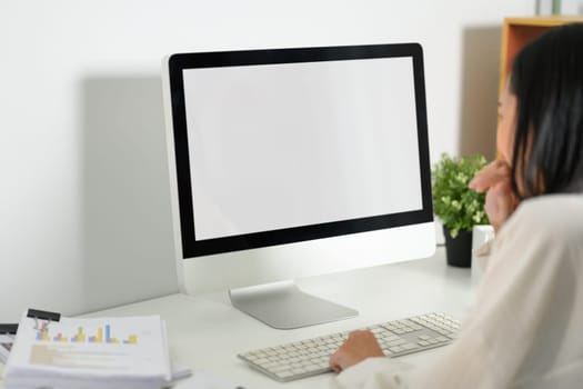 Businesswoman sitting in front of blank screen computer and typing on the keyboard.