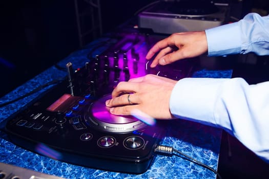hands of DJ closeup playing music on the club mixer