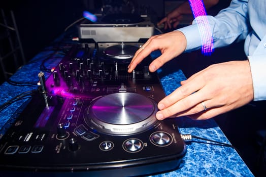 club DJ mixing music on a mixer in nightclub