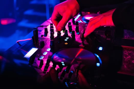 DJ mixes and controls controls music on professional equipment with coloured lights