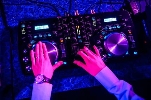 DJ driving music on professional equipment in nightclub, view from above