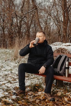 Winter Serenity: 40-Year-Old Man Enjoying Tea on Snow-Covered Bench in Rural Park. Immerse yourself in the tranquil beauty of winter as a 40-year-old man finds solace on a snowy bench in a rural park. Sipping hot tea from a thermos, he embraces the serene ambiance, surrounded by the peaceful, snow-covered nature. This captivating image captures the essence of winter leisure, offering a moment of seasonal joy and quiet contemplation amidst the breathtaking scenery.