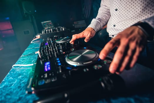 DJ plays music at the night club at the party by controlling the buttons and levels