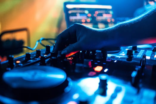 hand of the DJ moves the volume control and mixing music on a mixer at a party in a nightclub