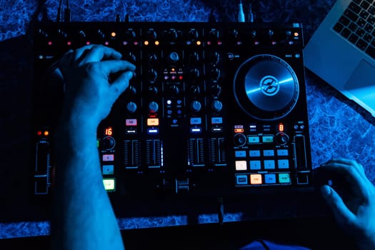 hands of DJ and professional music equipment mixer controlling buttons and levels music the view from the top