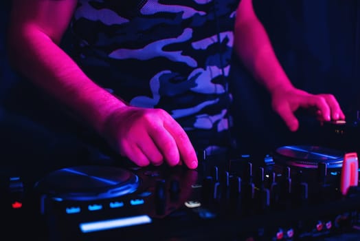 DJ playing in nightclub on the mixer and a professional equipment for color spotlight