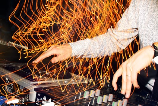 DJ hands mix music on professional mixer in booth at a party in nightclub