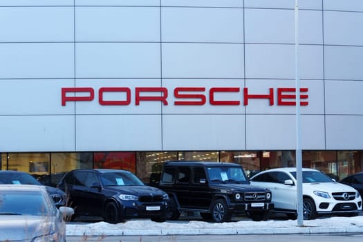 Tyumen, Russia-March 18, 2024: Cars parked in rows in front of a Porsche dealership, showcasing various models and colors available for sale.