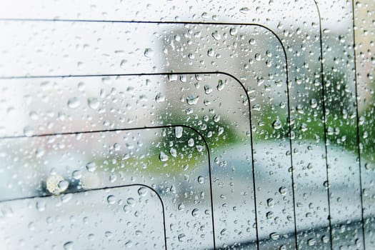 raindrops on the surface of the car glass in rainy weather with a blurred background on the street