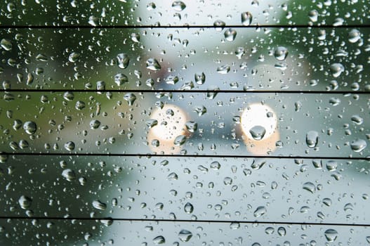 raindrops on the surface of the car glass in rainy weather with a blurred background on the street