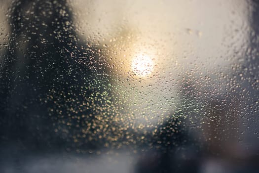 raindrops on the surface of the car glass in rainy weather with a blurred background on the street