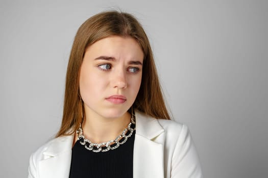 Young Woman Expressing Discontent against gray background in studio