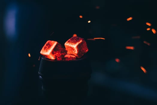 hot red coals with hookah sparks in metal bowl for Shisha Smoking and traditional Asian relaxation close up