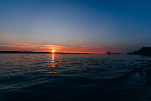 beautiful sunset on the river with the outgoing red sun and the blue sky