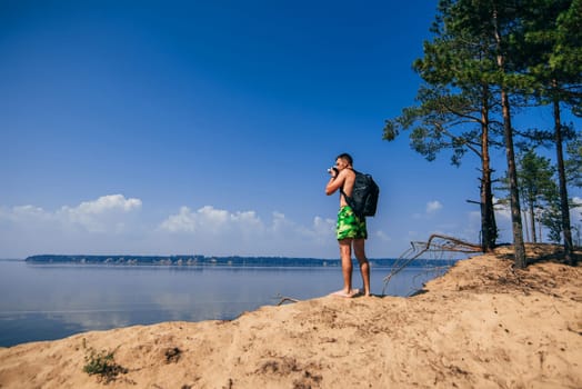 traveler photographer with backpack taking pictures of summer
