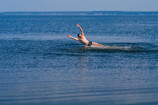 man swims and having fun resting in the water with the spray in summer on the beach