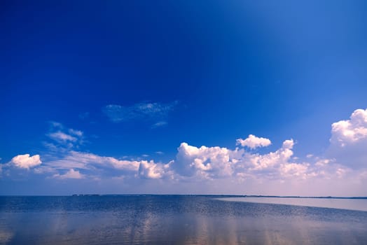 blue clear sky with white clouds over the water on a summer day