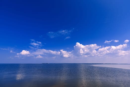 blue clear sky with white clouds over the water of the river on a Sunny summer day