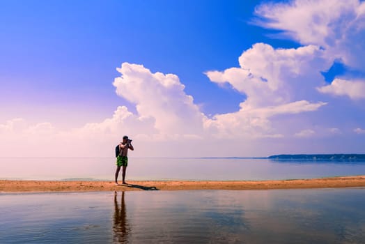 traveler photographer a European with a backpack taking pictures of the water in the summer
