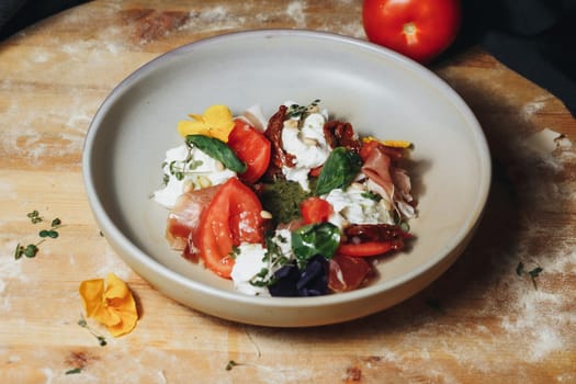 Ripe red tomatoes and chunks of cheese sitting beautifully on a wooden cutting board.