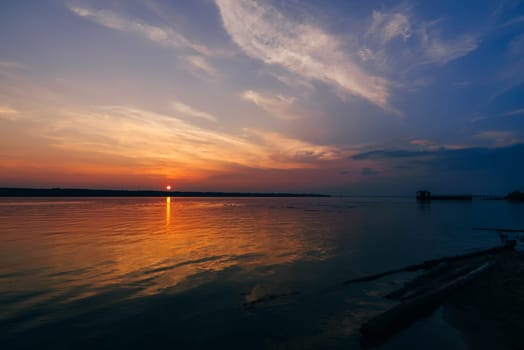 sunset over the river and a beautiful sky on a summer evening and the silhouette of the pier