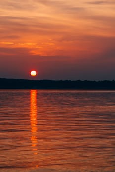 sunset on a summer evening with a big sun over the water of the sea vertical
