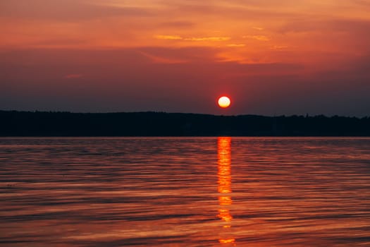 big red sun at sunset with orange sky over the sea
