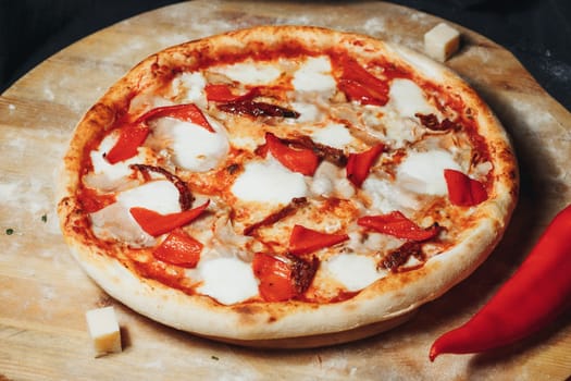 A freshly baked pizza topped with vibrant peppers and gooey cheese rests on a wooden cutting board.