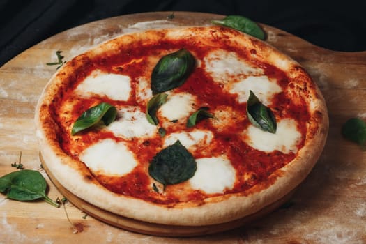 Freshly baked pizza with melted mozzarella cheese and aromatic basil placed on a rustic wooden cutting board.