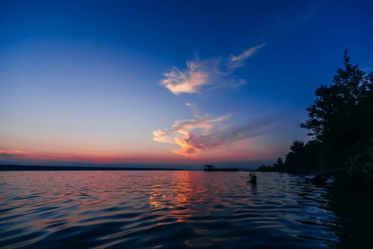 sunset over the water with a jetty on a summer evening on the sea with a red blue background