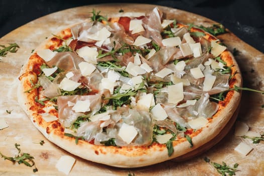 A freshly baked pizza topped with parmesan cheese and vibrant arugula leaves on a rustic wooden board.