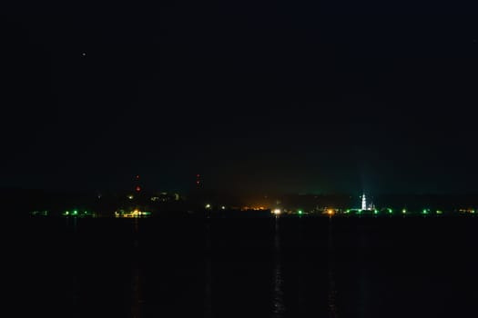 small town lights on the river with reflection in water on a dark night