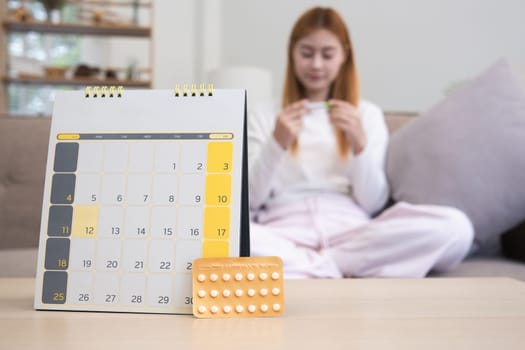 A young woman with a calendar and birth control pills reads instructions on how to use them correctly..