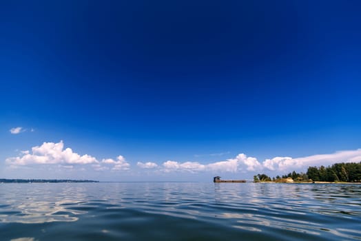 blue clear sky with white clouds over the water on a summer day